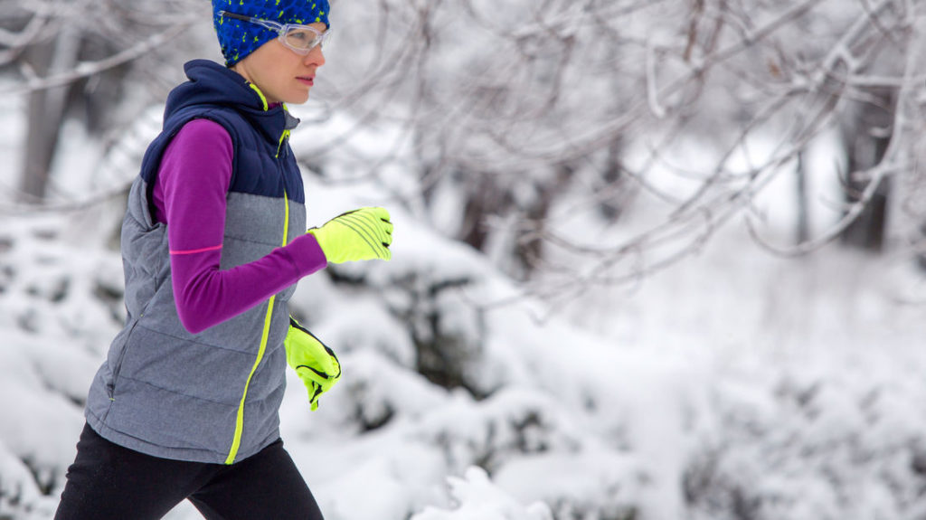 Frau mit Laufhandschuhen läuft im Winter