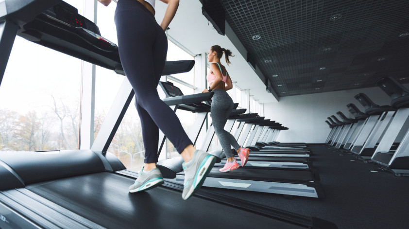 Zwei junge Frauen auf Laufbändern man das 12-3-30 Laufband Workout von Lauren Giraldo