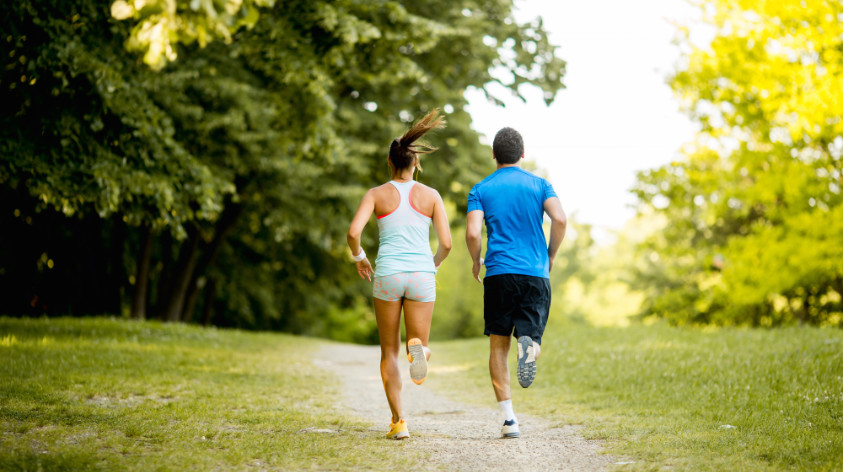 Junges Paar beim Fahrtspiel Lauftraining auf einer Wiese mit Bäumen